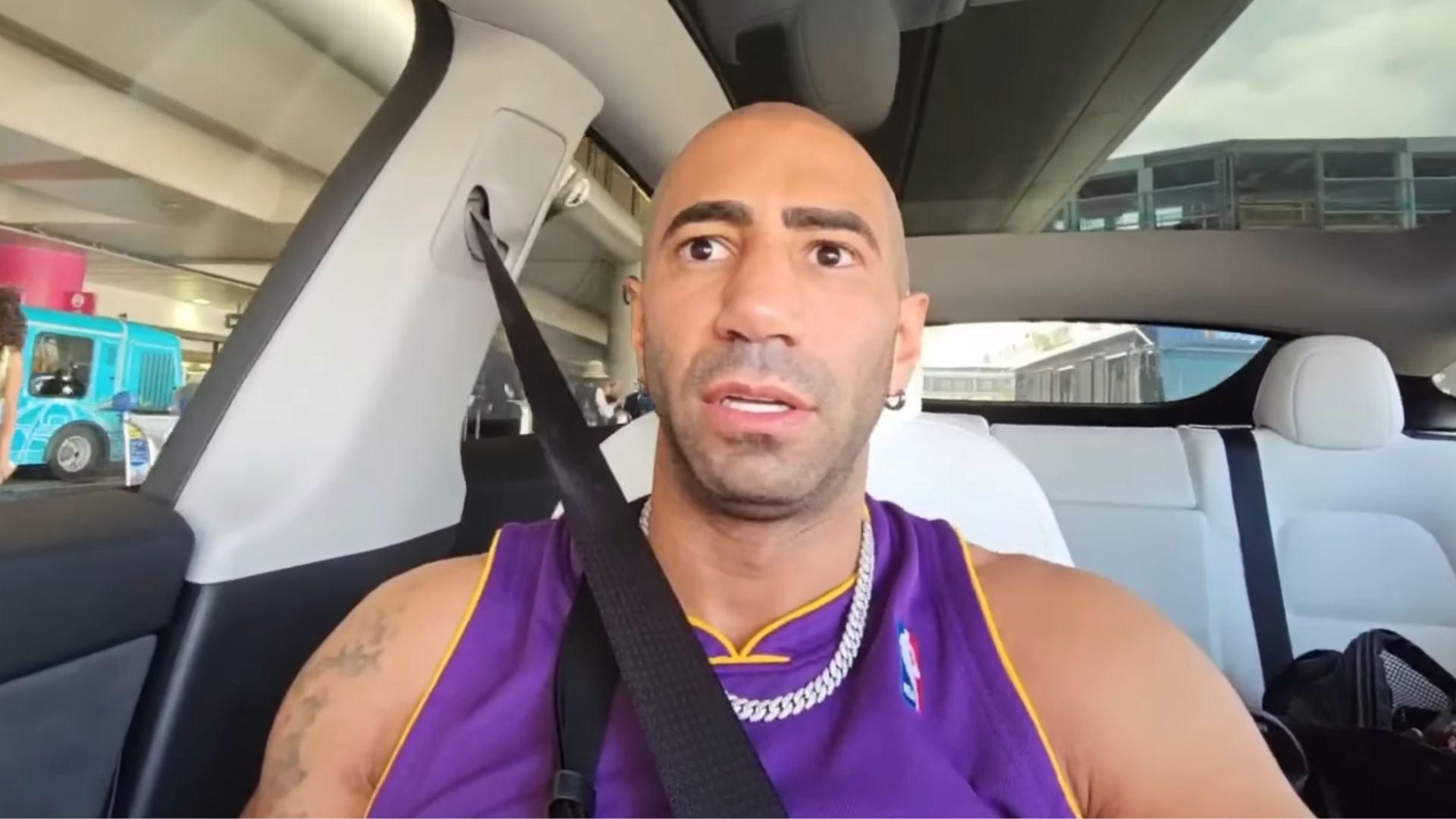 Fousey in purple and yellow laker shirt sat in car talking to camera.